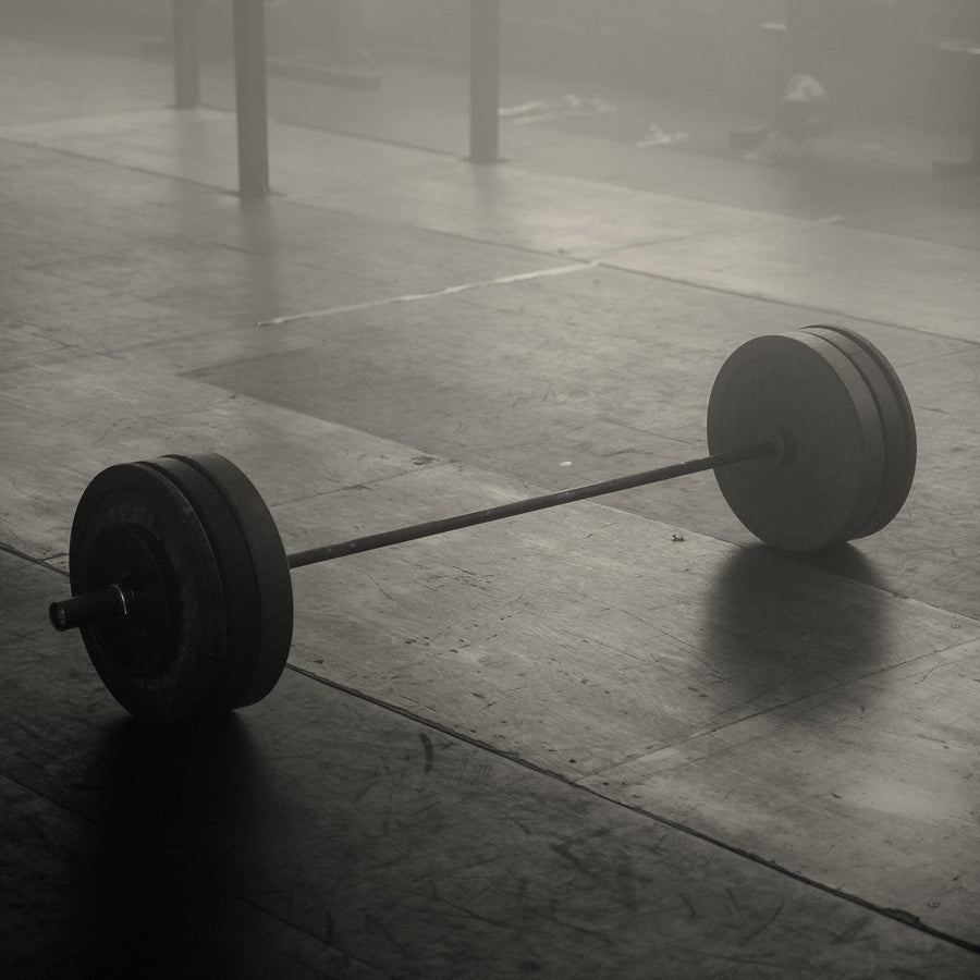 Loaded barbell resting on an empty gym floor
