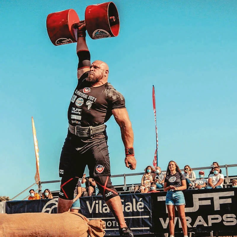 Travis Ortmayer pressing a circus dumbbell overhead at SCL Portugal 2021